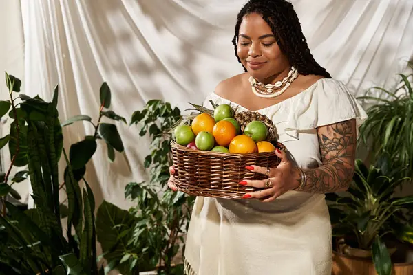 A beautiful woman with braids wears a summer dress while holding a basket of fresh fruit. — Stock Photo
