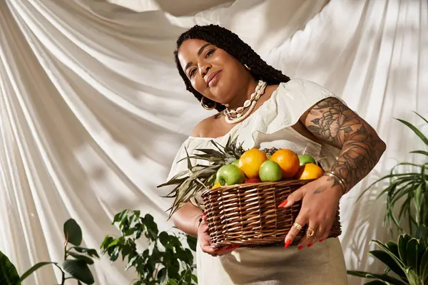 A pretty African American woman in a summer dress poses joyously with a basket of fruits. — Stock Photo