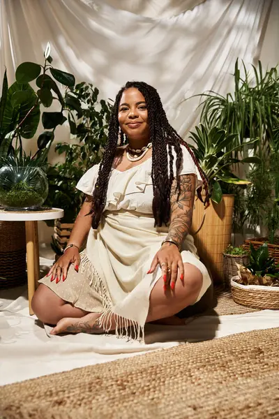 Una gioiosa donna afroamericana con trecce gode di un momento sereno circondata da lussureggianti piante verdi. — Foto stock