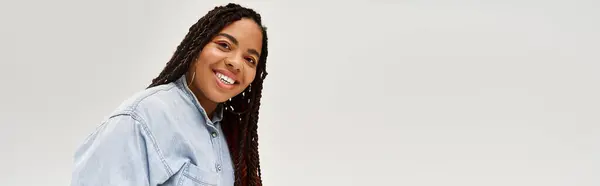 Cheerful African American woman showcases her style in a denim ensemble against a grey backdrop, banner — Stock Photo