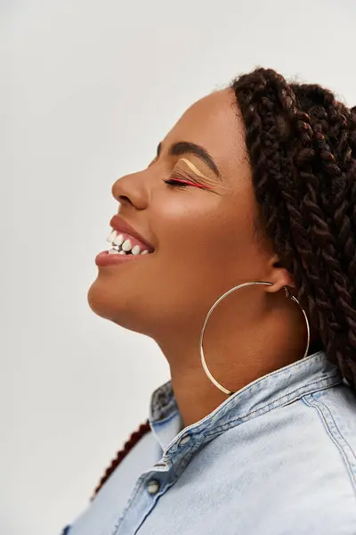 Una donna afroamericana fiduciosa con le trecce mette in mostra il suo spirito gioioso mentre posa con grazia. — Foto stock