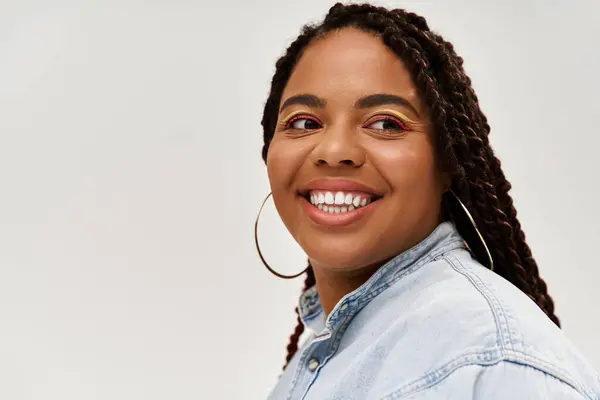 A pretty African American woman joyfully poses in a denim outfit against a grey backdrop. — Stock Photo