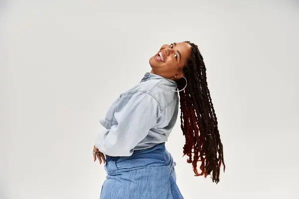 A beautiful African American woman with braids enjoys a joyful moment in denim attire in the studio. — Stock Photo