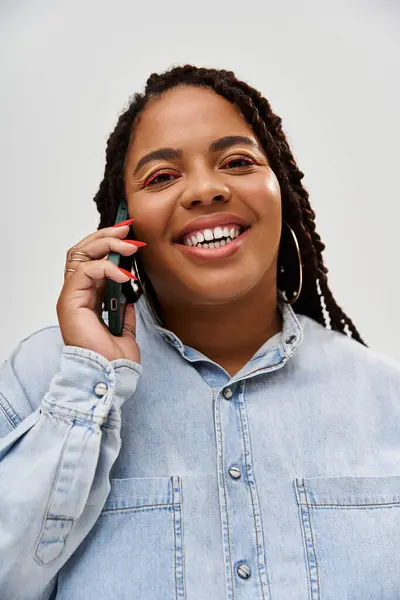 Una mujer alegre con trenzas se involucra en la conversación, mostrando su elegante look denim. - foto de stock