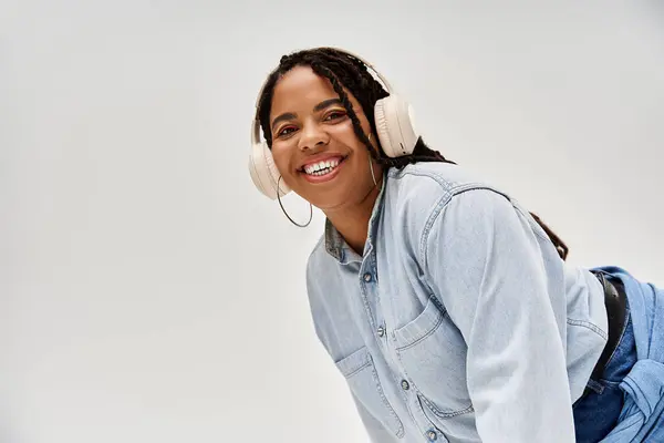 Una donna afroamericana allegra con le trecce posa in un elegante vestito di denim, godendo il momento. — Foto stock