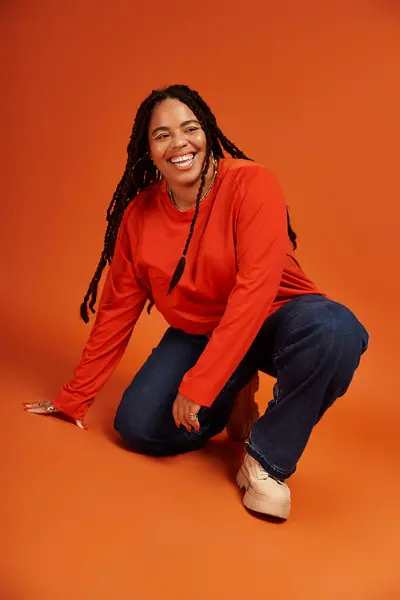 A joyful African American woman with braids poses playfully in a casual outfit, exuding confidence. — Stock Photo