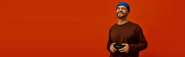 Cheerful young man dressed casually holds a gaming controller while smiling in a bright room. — Stock Photo