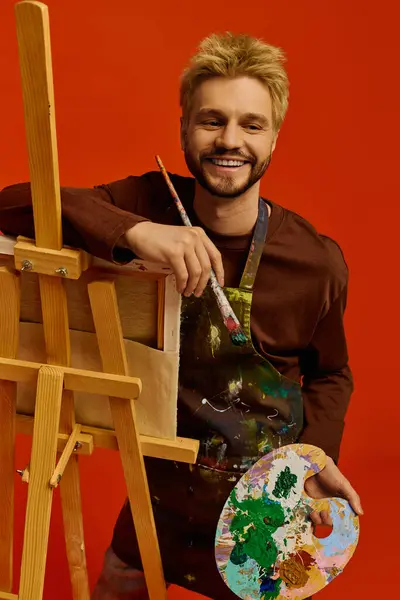 Guapo joven posa con un pincel y una paleta, mostrando su talento artístico. - foto de stock