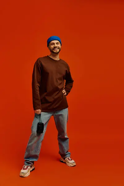 Handsome young man stands with a smile, wearing casual attire and a beanie, in a colorful setting. — Stock Photo