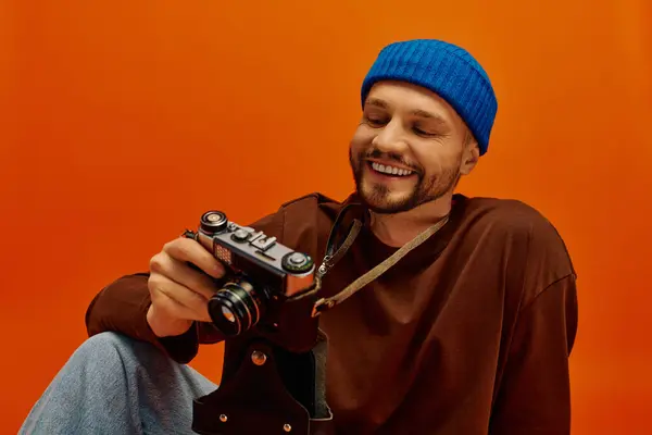 A young man smiles brightly while admiring his vintage camera in a cozy indoor space. — Stock Photo