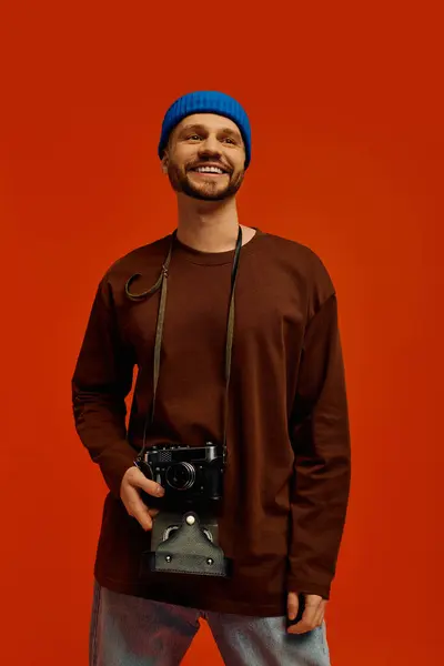 A young man in a blue beanie and brown shirt radiates joy and loves photography. — Stock Photo