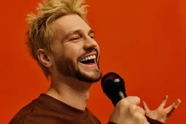 Joven guapo canta alegremente en un micrófono, exudando carisma y energía. - foto de stock