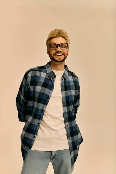 Sorriso luminoso e abbigliamento alla moda mostrano un giovane fiducioso in uno sfondo minimalista. — Foto stock