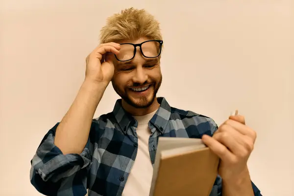 Young man smiles joyfully while holding a notebook, immersed in his thoughts and creativity. — Stock Photo