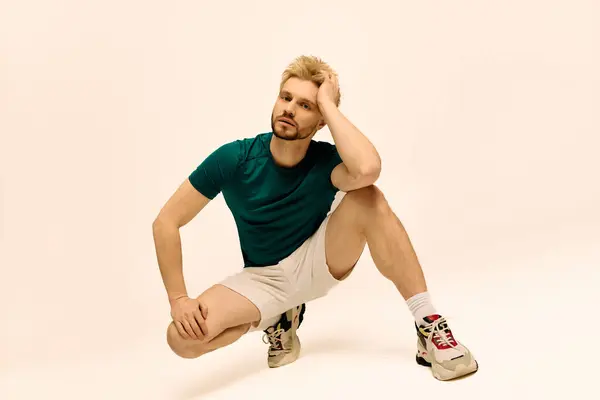 Un giovane uomo in camicia verde acqua e pantaloncini mostra creatività mentre posa in uno studio. — Foto stock