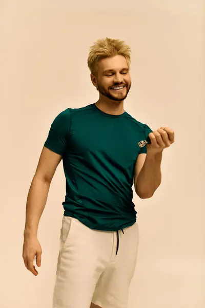 Un giovane allegro in camicia verde e pantaloncini leggeri sorride in un ambiente luminoso. — Foto stock