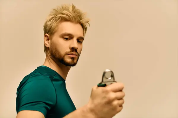 Ein gutaussehender junger Mann mit blonden Haaren posiert selbstbewusst und hält einen eleganten Gegenstand in der Hand. — Stockfoto
