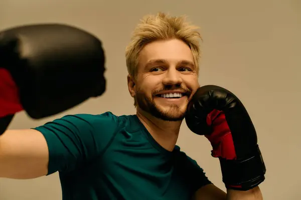Giovane energico mette in mostra le sue mosse di boxe con un sorriso fiducioso e guanti da allenamento. — Foto stock