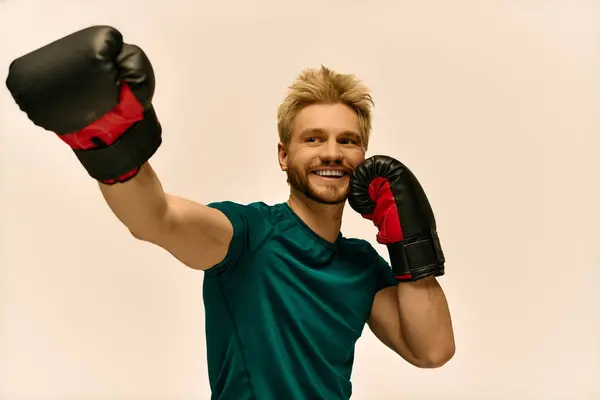 Un giovane allegro lancia un pugno giocoso in guanti da boxe in un ambiente vivace. — Foto stock