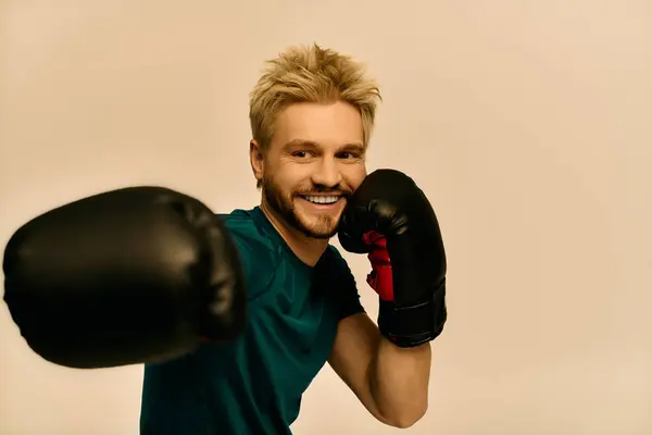 Un joven con rasgos llamativos demuestra movimientos de boxeo, sonriendo con confianza mientras entrena. - foto de stock