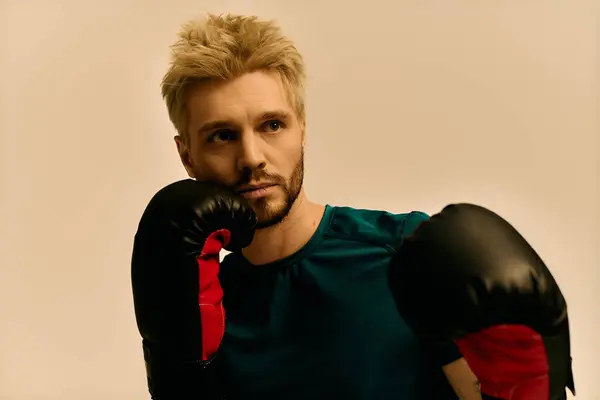 Strong and handsome young man reflects with intensity while wearing boxing gloves, showcasing focus. — Stock Photo