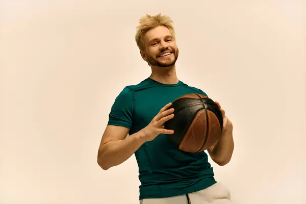 A cheerful young man is posed with a basketball, exuding confidence and energy while smiling. — Stock Photo