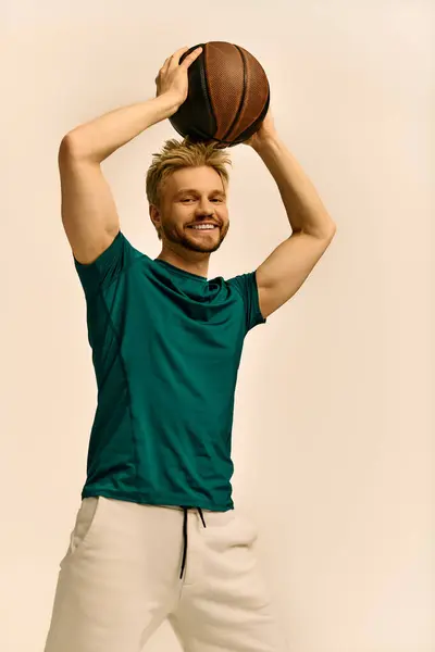 Un giovane gioioso solleva un pallone da basket, mostrando il suo atletismo ed entusiasmo. — Foto stock