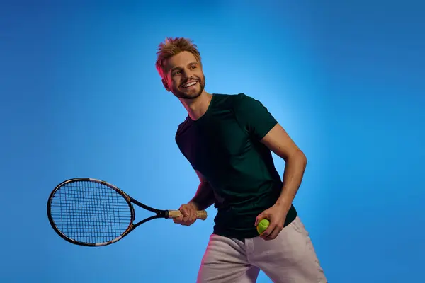 Bello giovane uomo gode di un vivace momento di tennis, tenendo una racchetta e sorridendo brillantemente. — Foto stock
