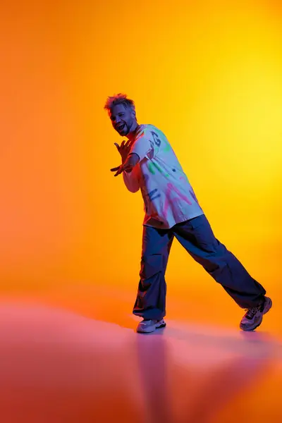 Un joven toma una pose lúdica sobre un fondo brillante y multicolor, mostrando su estilo. - foto de stock