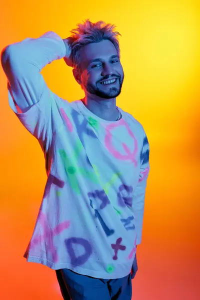 A smiling young man poses confidently, showcasing artistic clothing against a colorful backdrop. — Stock Photo