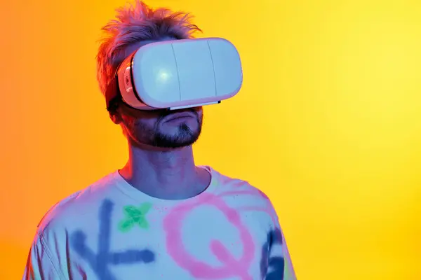 A handsome young man immerses himself in virtual reality against a colorful background. — Stock Photo