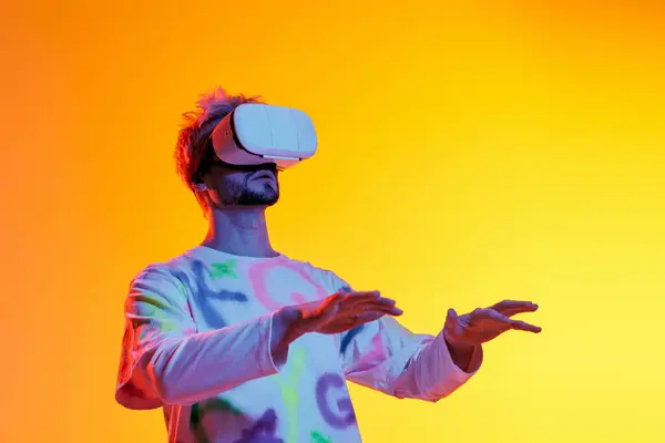 A young man explores a vivid virtual world, captivated by his VR goggles. — Stock Photo