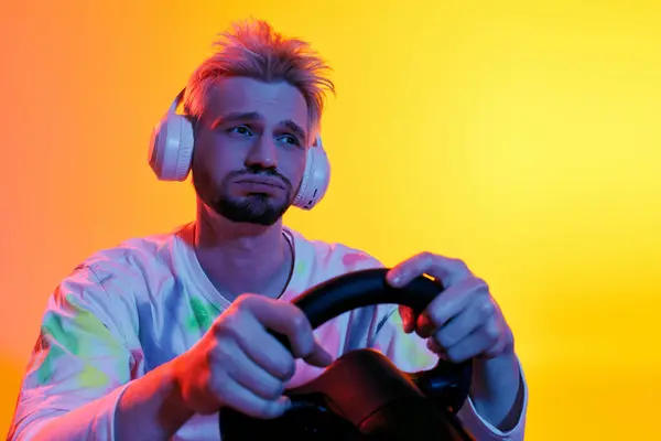Giovane uomo guida una ruota da gioco, focalizzata e immersa, con illuminazione colorata che migliora l'umore. — Foto stock