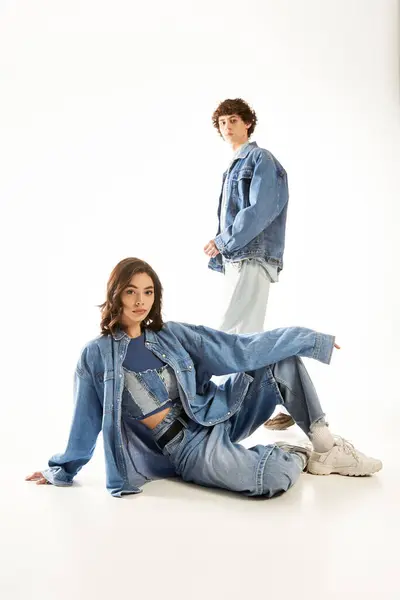 A stylish couple in trendy denim outfits expresses their love and connection in a bright studio. — Stock Photo