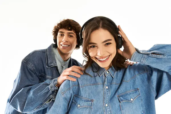 Gioiosa coppia condivide un momento d'amore mentre indossa cuffie e abiti in denim alla moda. — Foto stock