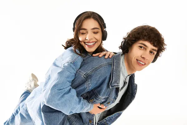 A joyful couple enjoys a fun moment in trendy outfits while listening to music. — Stock Photo