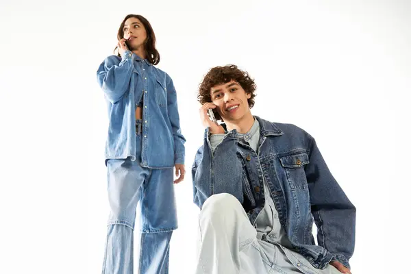Elegante pareja comparte una conversación de corazón ligero en vaqueros de moda, irradiando energía juvenil. - foto de stock