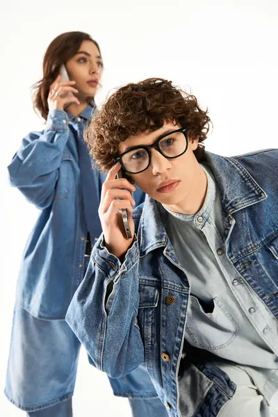 Un par de amantes jóvenes de moda interactúa juguetonamente, cada uno profundamente absorto en sus teléfonos. - foto de stock