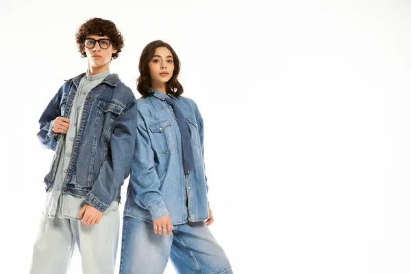 Stylisches junges Paar posiert selbstbewusst in trendigen Jeans-Outfits in einem lebhaften Rahmen. — Stockfoto
