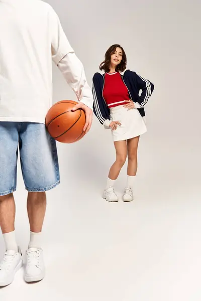 Una pareja con estilo comparte un momento lúdico, mostrando sus trajes de moda y el amor por el baloncesto. - foto de stock