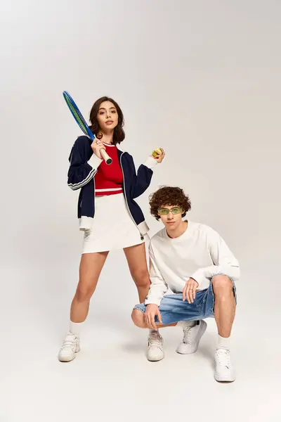 Young couple enjoys a playful moment with tennis gear, showing off their style and love. — Stock Photo