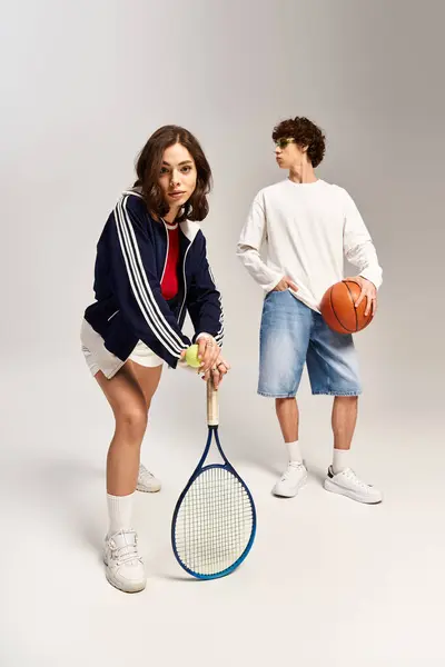 Giovane coppia mette in mostra il loro atletismo e stile di moda, mentre impegnarsi in tennis e basket. — Foto stock
