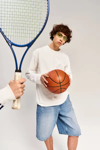 Love shines as a stylish couple enjoys a playful moment with a basketball and tennis racquet. — Stock Photo