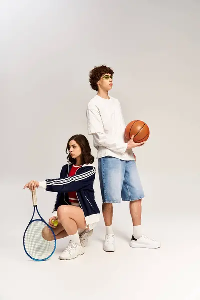Stylish couple showcases their athletic side in a modern studio with basketball and tennis gear. — Stock Photo