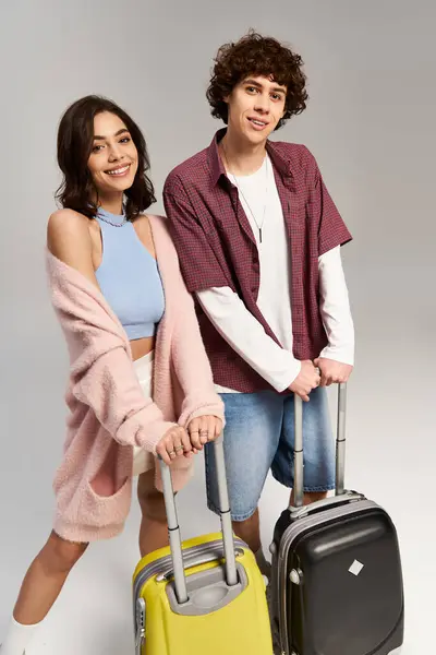 Casal jovem sorri brilhantemente enquanto segura sua bagagem na moda, ansioso para viajar e explorar. — Fotografia de Stock