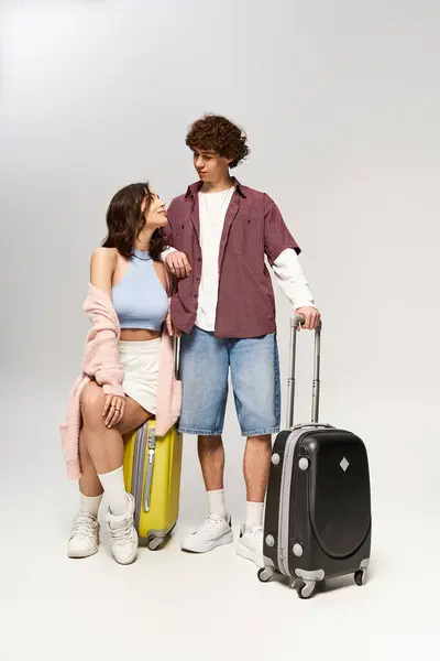 Stylish couple stands together, smiling with anticipation and holding suitcases. — Stock Photo