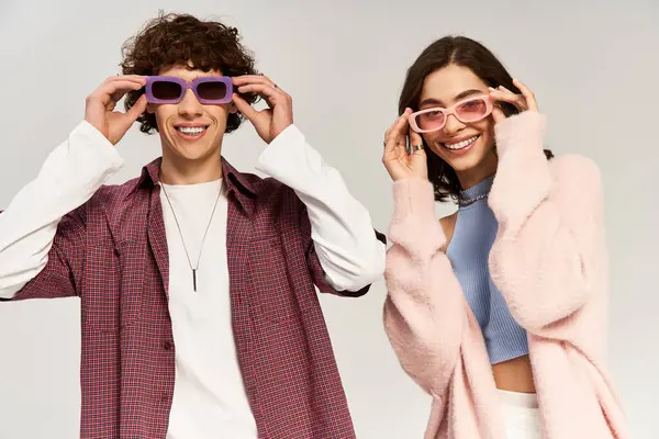 A young couple enjoys a joyful moment in trendy purple sunglasses, showing off their playful style. — Stock Photo