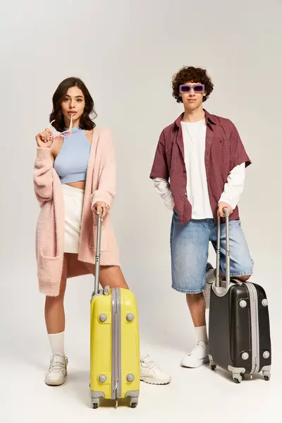 A fashionable couple poses confidently with their colorful luggage, showcasing love and style. — Stock Photo