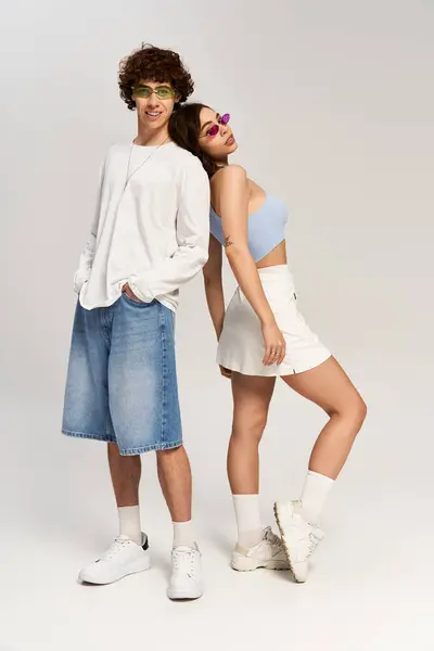 Gioioso coppia posa back to back, ostentando abiti alla moda in un ambiente vibrante. — Foto stock