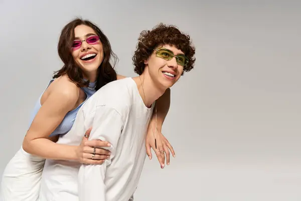 Una pareja con estilo irradia alegría mientras posan juguetonamente en gafas de sol de moda. - foto de stock